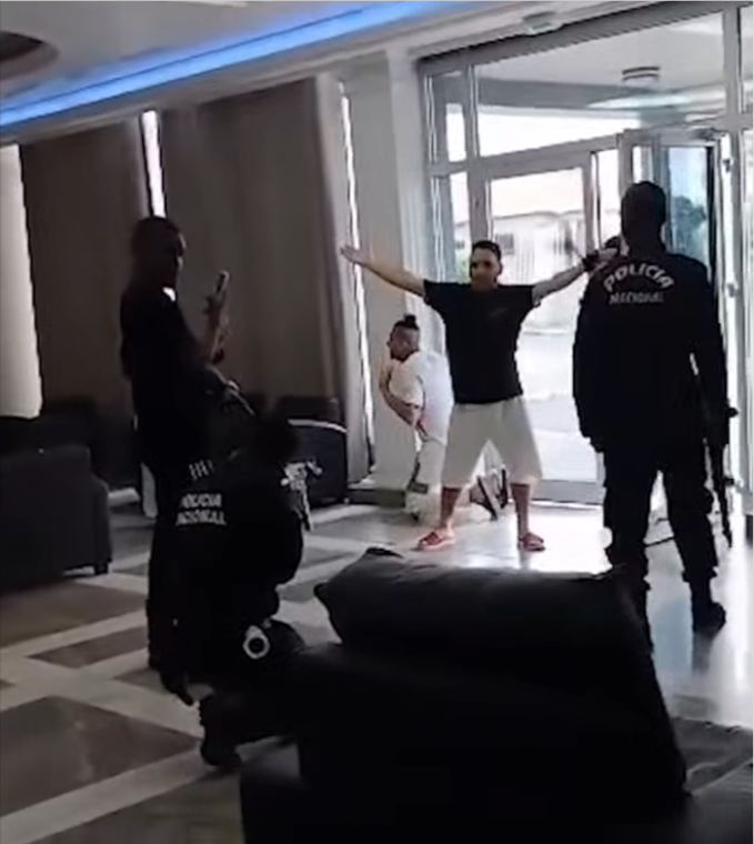 Ahmed Soliman, in the white shirt on his knees, is shielded by another deportee as armed police surround them in Equatorial Guinea following their deportation from the United States.